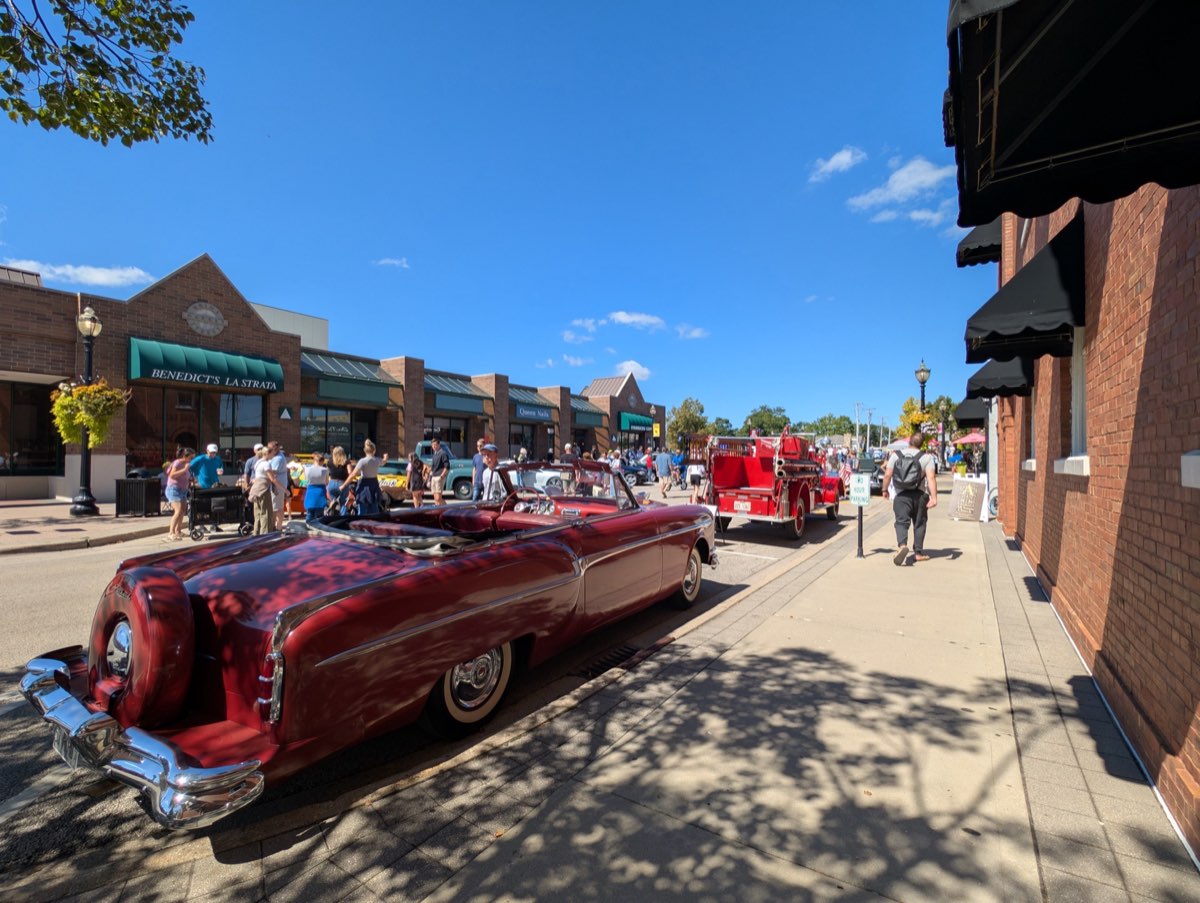 Red convertible with crowds on the street
